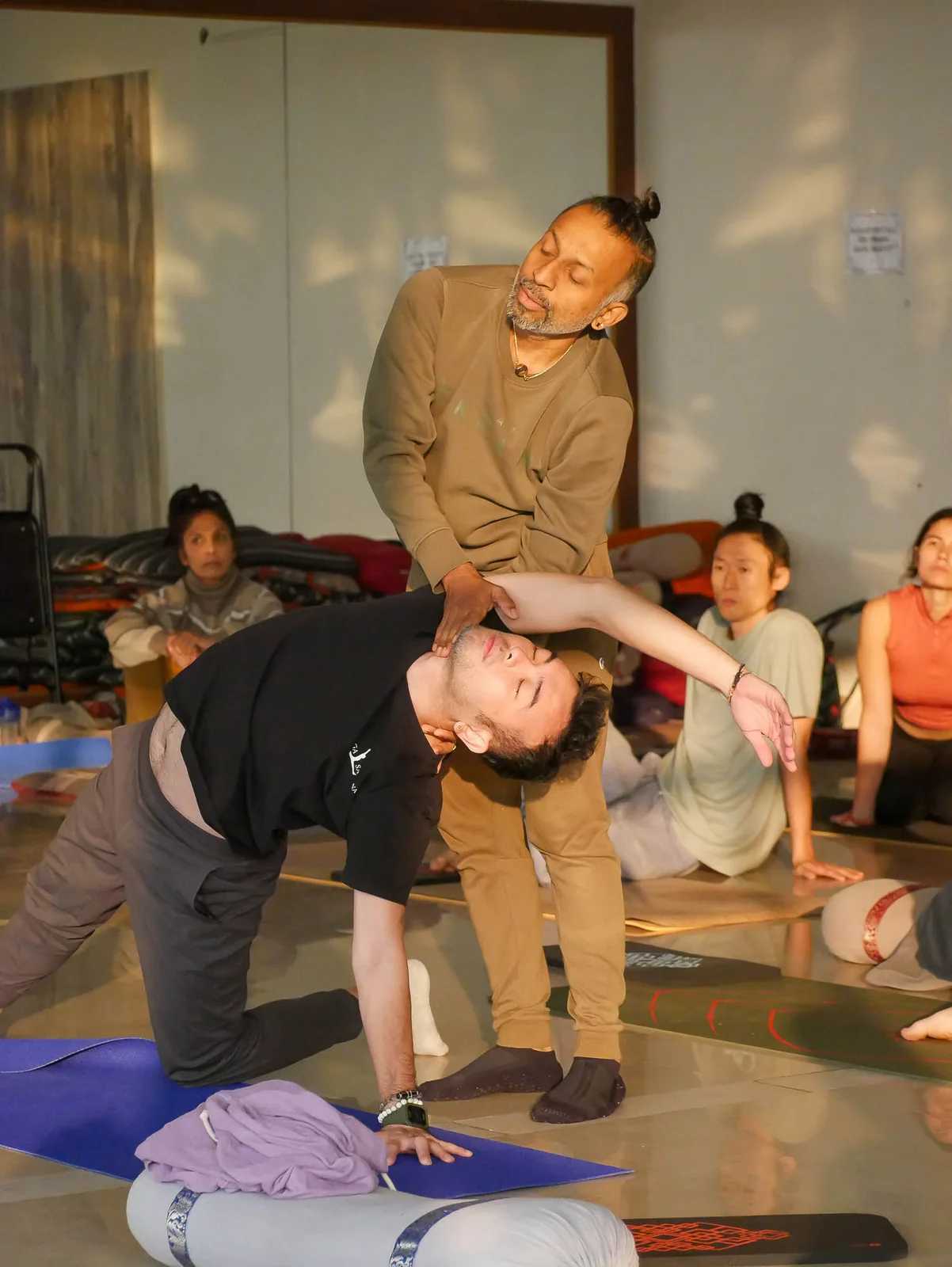 Parveen Nair supporting a student through a backbend on the floor