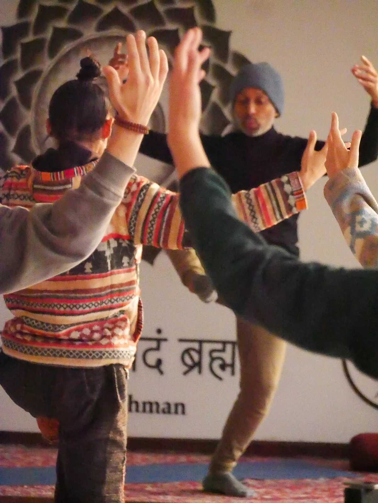 Parveen Nair among a group with hands raised, in front of a wall painted with Sanskrit