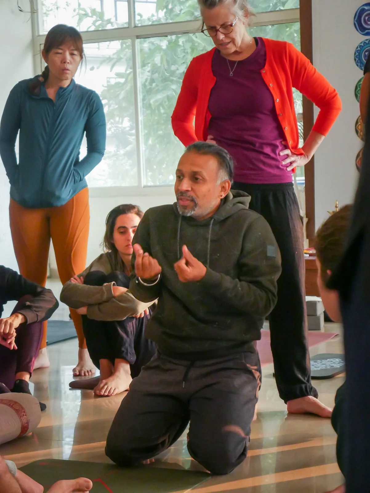 Parveen Nair kneeling as he explains a movement to the room