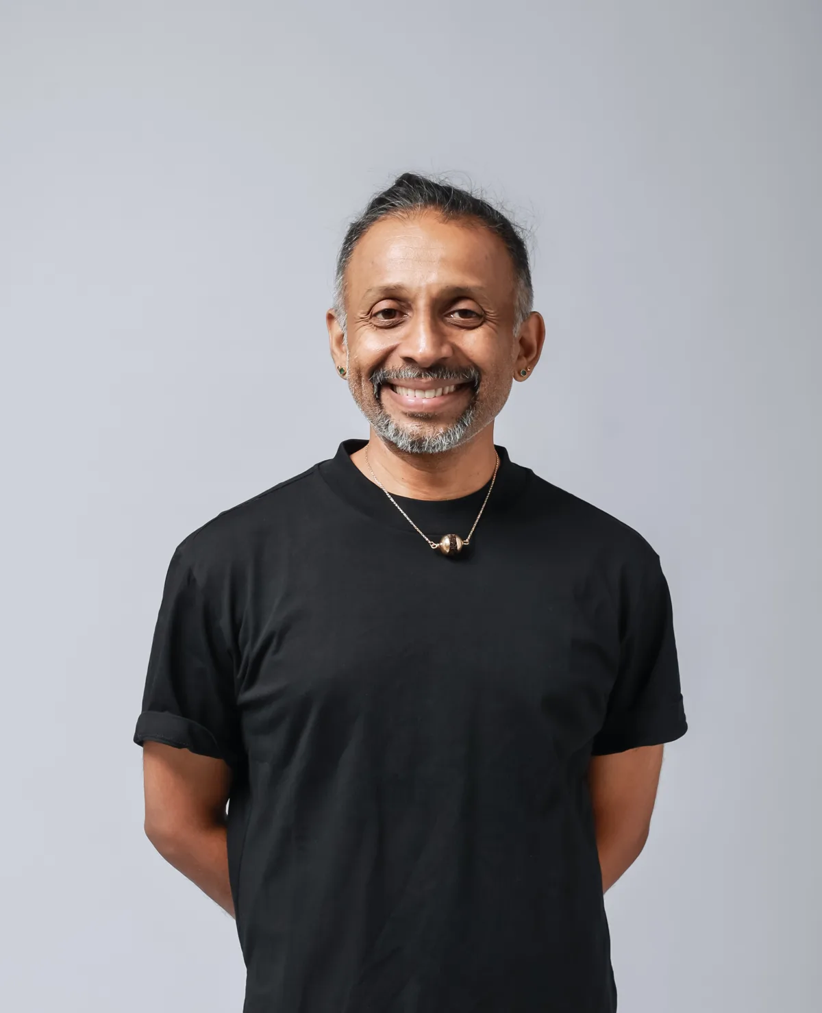 A portrait of Parveen Nair, smiling, in a black T-shirt