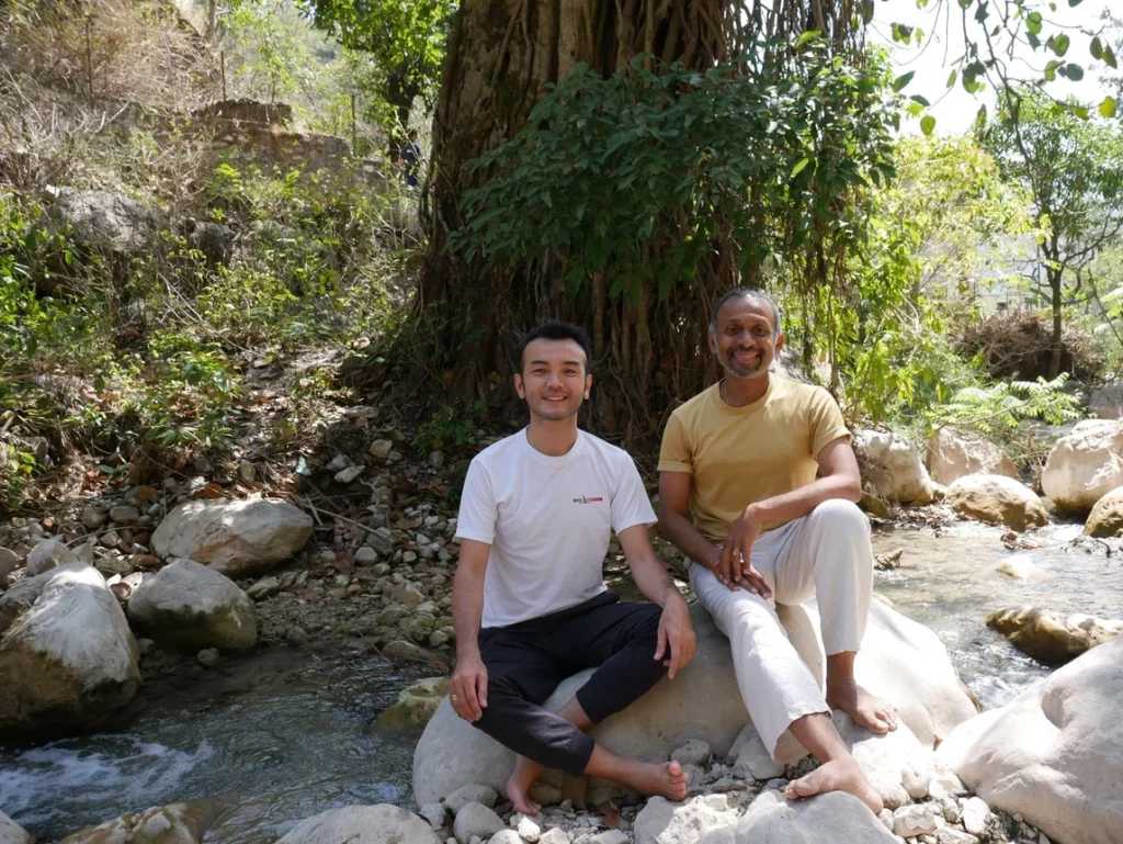 Parveen Nair sitting by the river with a student