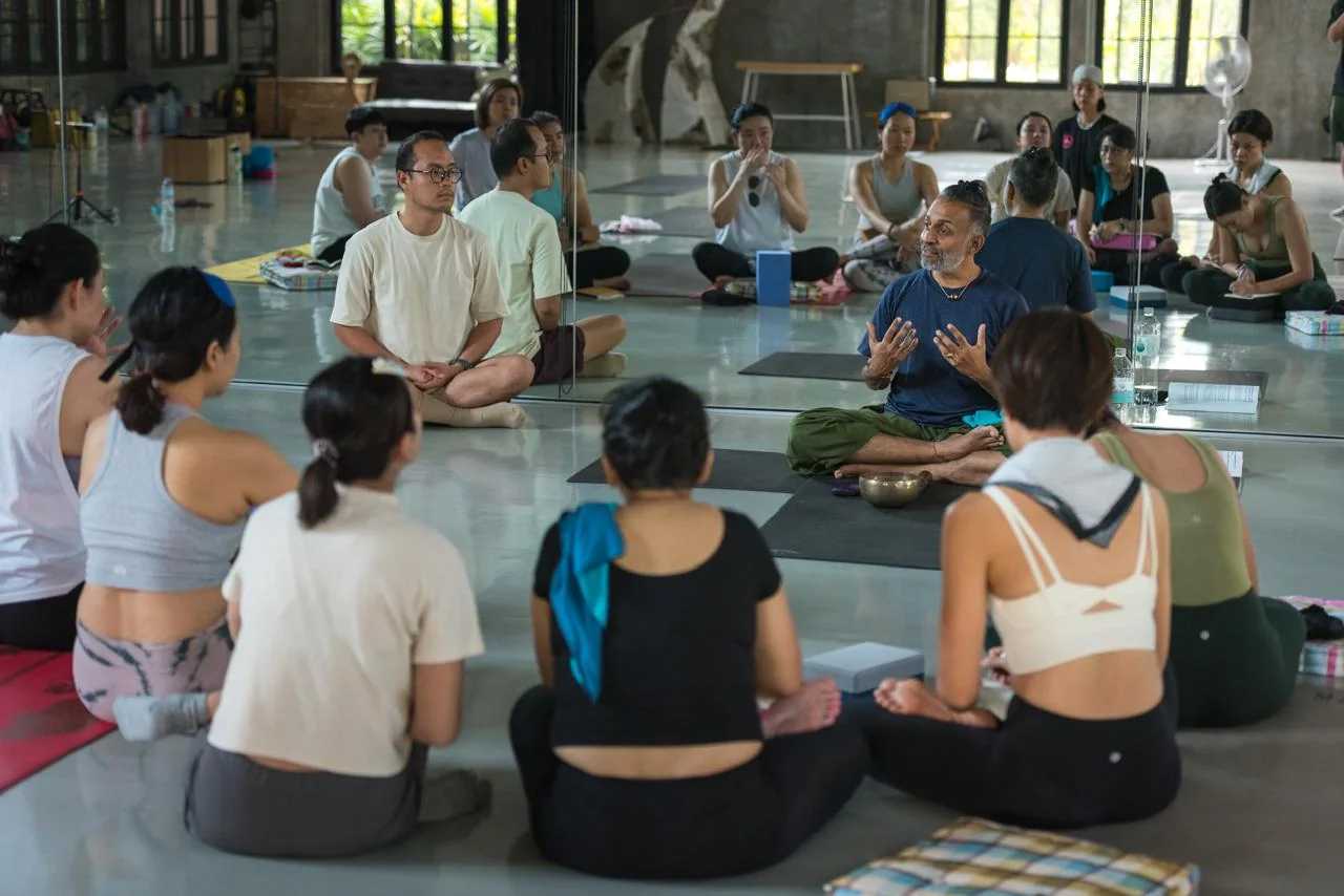 A wide circle of students sitting together on the studio floor